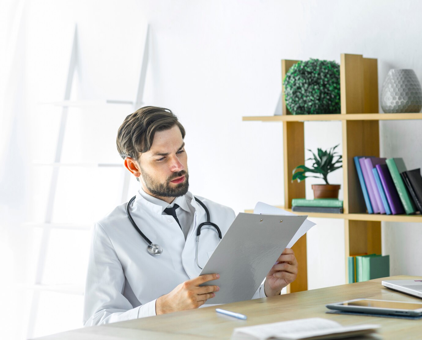 Doctor reviewing patient documents at a desk with a laptop